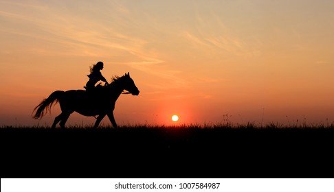 Horseback Woman Riding On Galloping Horse With Red Rising Sun On Horizon. Beautiful Colorful Sunset Header Background With Equine And Girls Silhouette. 