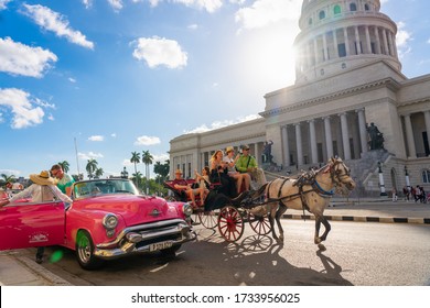 Horse-drawn car with tourists and a convertible classic car in front of the Havana Capitol, this is one of the most visited places by foreign tourists. Havana. Cuba. January 6, 2020.