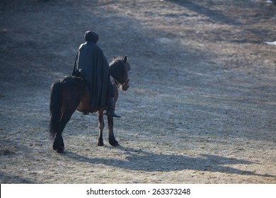 Horseman, knight in black, riding on a black horse in the meadow 