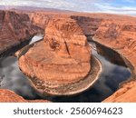 Horseshoe Bend is a mesmerizing natural wonder where the Colorado River makes a dramatic, horseshoe-shaped curve through vibrant red sandstone cliffs. Standing at the edge of the overlook, you’re gree