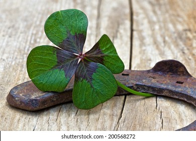 horseshoe and four leaf clover on wood - Shutterstock ID 200568272
