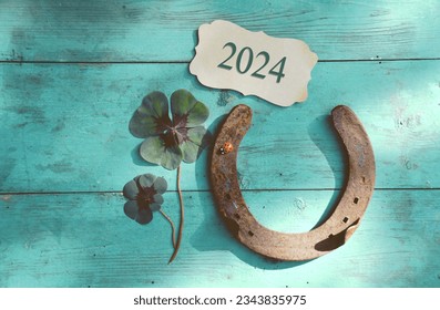 Horseshoe with lucky clover - 2024 greeting card - horseshoe with ladybird on wooden background - happy new year and birthday greetings, wishes
					