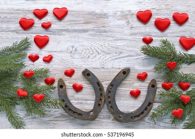 Horseshoes with christmas tree, red hearts on wooden background 
