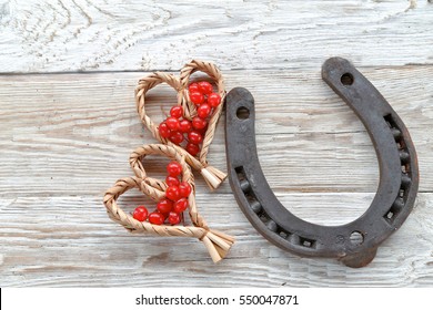 Horseshoes with  straw hearts with red berries on wooden background 