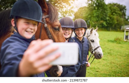 Horsing around on the ranch. Shot of a group of young friends taking a selfie while going horseback riding. - Powered by Shutterstock