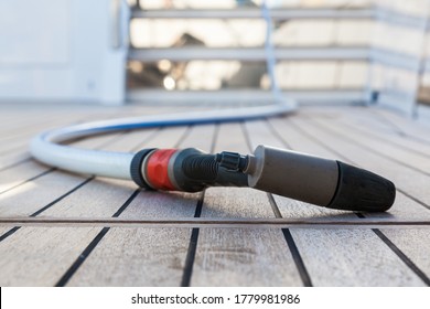 Hose with a gun for washing yachts on the teak deck of a yacht, close-up.