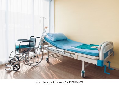 Hospital bed with pillow and blanket and intravenous (IV) stand and walking stick and wheelchair, No patient in the room in the modern hospital. Healthcare, medical insurance concept. - Powered by Shutterstock