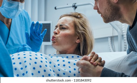 In the Hospital, Close-up on a Woman in Labor Pushing Hard to Give Birth, Obstetricians Assisting, Spouse Holds Her Hand. Modern Maternity Hospital with Professional Midwives. - Shutterstock ID 1181843092