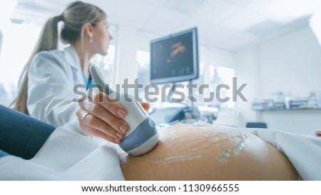 In the Hospital, Close-up Shot of the Doctor does Ultrasound / Sonogram Procedure to a Pregnant Woman. Obstetrician Moving Transducer on the Belly of the Future Mother.