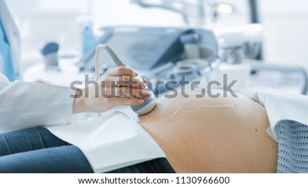 In the Hospital, Close-up Shot of the Doctor Doing Ultrasound / Sonogram Scan to a Pregnant Woman. Obstetrician Moving Transducer on the Belly of the Future Mother.
