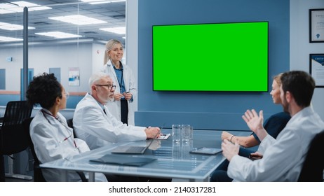Hospital Conference Meeting Room: Female Doctor Presents Chroma Key Green Screen TV to a Team of Medical Professional. Research Scientists Discuss Patient Treatment, Drugs and Medicine Development