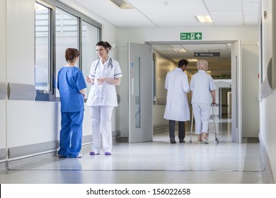 Hospital corridor with doctors, nurses & senior female patient