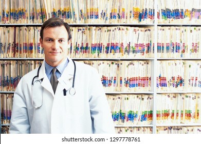 Hospital Doctor In Front Of Medical Records On Shelves Looking At Camera