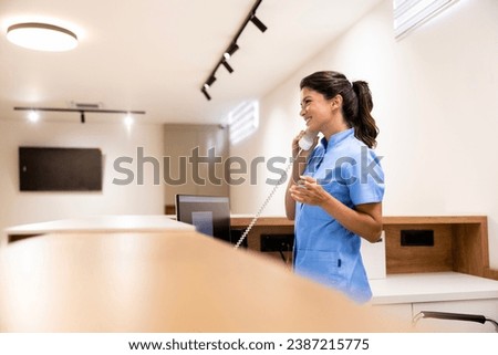 Hospital front desk receptionist talking on the phone and making doctor appointment.