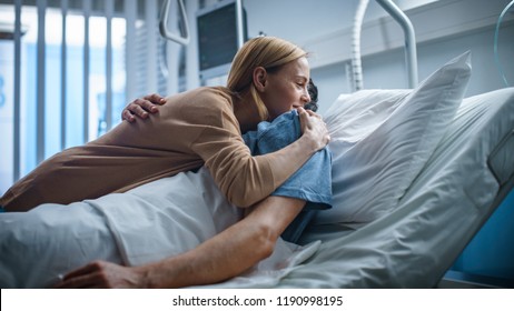 In the Hospital, Happy Wife Visits Her Recovering Husband who is Lying on the Bed. They Lovingly Embrace and Smile.