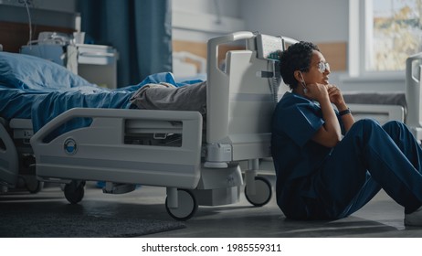 Hospital Intensive Care Coronavirus Ward: Portrait Of Sad, Tired Black Nurse Taking Off Face Mask Sitting On A Floor, Sorry For All The Patients Lost To Pandemic. Brave Hero Paramedics Save Lives