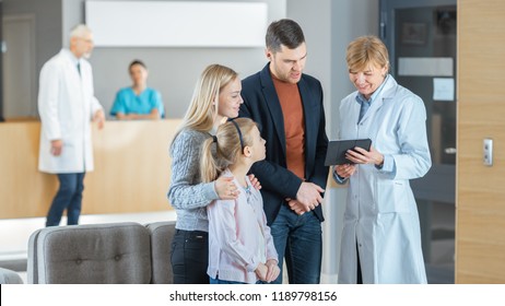 In the Hospital Lobby Female Doctor Shows Information on the Tablet Computer to the Young Family (Father, Mother and Little Daughter). They all Smile and Are Happy. Modern and Busy Medical Facility. - Powered by Shutterstock