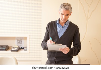 Hospital male receptionist writing down appointments on clinic schedule folder.