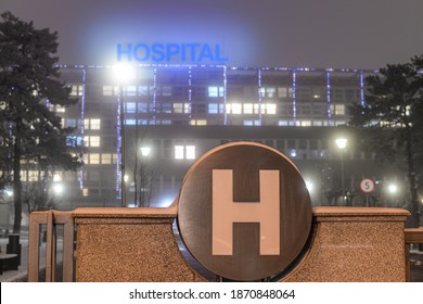 Hospital At Night In December With Snow And A Big H In Front Of The Building