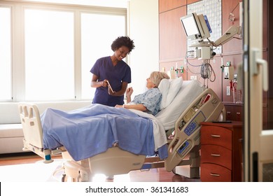 Hospital Nurse With Digital Tablet Talks To Senior Patient