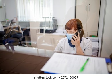 At The Hospital, The Nurse On Duty Speaks On The Phone At The Reception Desk. Busy Modern Hospital With Some Of The Best Specialists And Medicare In The Country.