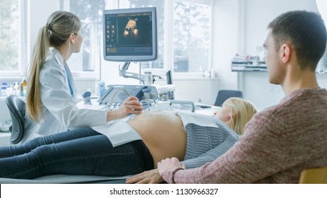 In the Hospital, Obstetrician Uses Transducer for Ultrasound/ Sonogram Screening Belly of the Pregnant Mother. Husband Supports His Wife and Holds Her Hand. - Powered by Shutterstock