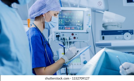 In The Hospital Operating Room Anesthesiologist Looks And Monitors And Controls Patient's Vital Signs, Nodding To A Chief Surgeon To Proceed With Surgery.