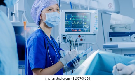 In The Hospital Operating Room Anesthesiologist Looks And Monitors And Controls Patient's Vital Signs, Nodding To A Chief Surgeon To Proceed With Surgery.