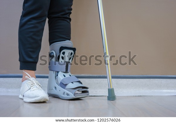 In\
the hospital, patients suffered from fracture of the ankle, needing\
to wear an orthopedic boot, and practice walking with crutch to\
maintain the balance. medical and orthopedic\
concept.