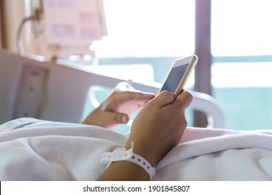 Hospital Patients woman senior using smart phone for reading news in mobile with hands medical drip intravenous needle, saline, Iv drip, give salt water on hospital bed, Health care technology concept - Powered by Shutterstock