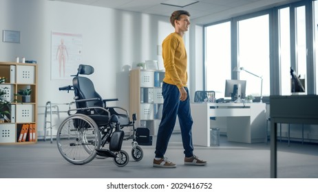 Hospital Physical Therapy: Determined Young Man With Injury Successfully Stands Up From Wheelchair And Walks. Miracle Of Rehabilitation, Strong Mindedness, Willpower, Professional Doctors.