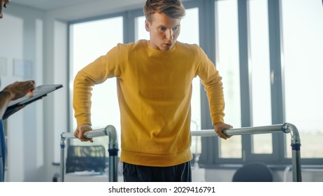 Hospital Physical Therapy: Portrait Of Strong Male Patient With Injury Successfully Walks Holding Parallel Bars. Physiotherapist, Rehabilitation Doctor, Help, Assist, Disabled Person.