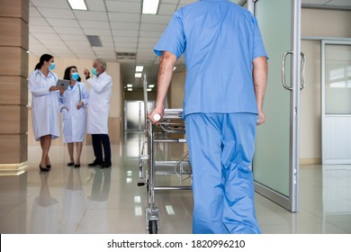 Hospital porter caring the stretcher troller while senior doctor therapist gp give consulting with a young women doctors by tablet computer in hospital. Multidisciplinary medical team in white coat. - Powered by Shutterstock