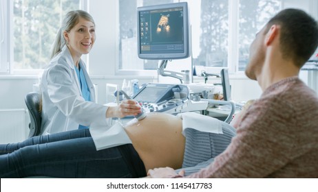 In the Hospital, Pregnant Woman Getting Ultrasound / Sonogram Scan, Obstetrician Explains Procedure to Her and Her Supportive Husband. Happy Family Waiting for their First Baby.