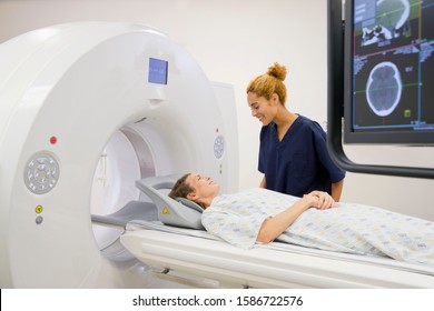 Hospital Radiographer With Female Patient Operating CT Scanner