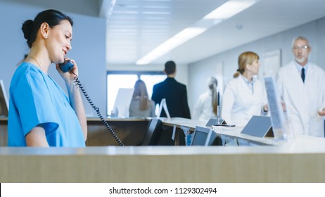 In the Hospital at the Reception Desk Nurse on Duty Talking on Phone. Busy Modern Hospital with Best Specialists and Medicare in Country.