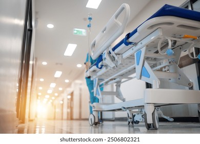 A hospital room with a medical staff member pushing a hospital bed. The room is bright and sterile, with a large window letting in natural light. The medical staff member is wearing a blue uniform - Powered by Shutterstock