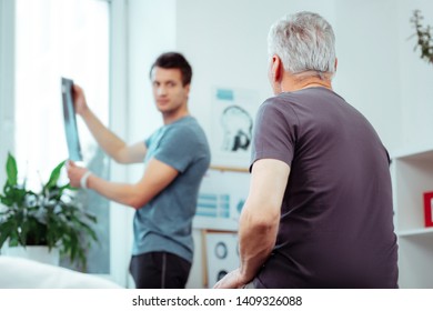 In The Hospital Room. Selective Focus Of A Nice Aged Man Looking At His Doctor