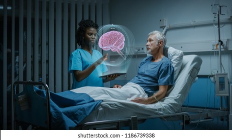 In the Hospital, Senior Patient Lying in the Bed Nurse Holding Tablet Computer Shows Augmented Reality Brain Scan. In the Technologically Advanced Hospital Ward.