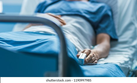 In the Hospital Sick Male Patient Sleeps on the Bed. Heart Rate Monitor Equipment is on His Finger. - Shutterstock ID 1190997985