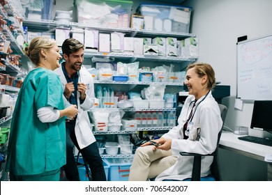 Hospital Staff Having Casual Discussion In The Pharmacy. Three Colleagues Meeting In Drugstore And Laughing.