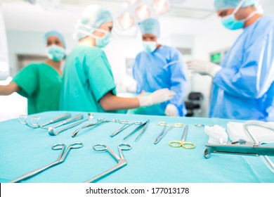 Hospital - surgery team in the operating room or Op of a clinic operating on a patient, perhaps it's an emergency a assistant holding a cotton swap forceps - Powered by Shutterstock