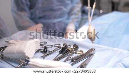 In the hospital, there is a tray with surgical instruments in the operating room. Veterinary surgeon starts knee surgery. Sterile surgical instruments are laid out on a blue background.