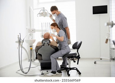 Hospital two doctors in medical uniform looking into sick pacient mouth analyzing teeth health preparing for stomatological surgery. Stomatologist doctors working in orthodontic clinic - Powered by Shutterstock