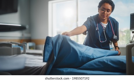 Hospital Ward: Beautiful, Professional Latin Black Nurse Working, Doing Bed, Cleaning Room After Happy Healthy Patients Recover and are Discharged Under Treatment of the Best Doctors. Sunny Room