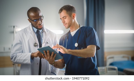 Hospital Ward: Black Doctor Talks With Professional Caucasian Head Nurse or Surgeon, They Use Digital tablet Computer. Diverse Team of Health Care Specialists Discussing Test Result in Modern Clinic