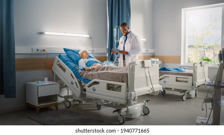 Hospital Ward: Friendly Black Doctor Talks to Beautiful Caucasian Female Patient Resting in Bed. Physician Uses Tablet Computer, Explains Test Results. Woman Recovering after Successful Surgery - Shutterstock ID 1940771665