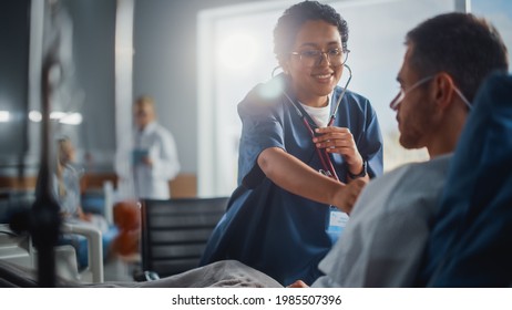 Hospital Ward: Friendly Black Head Nurse Uses Stethoscope to Listen to Heartbeat and Lungs of Recovering Male Patient Resting in Bed, Does Checkup. Man Getting well after Successful Surgery