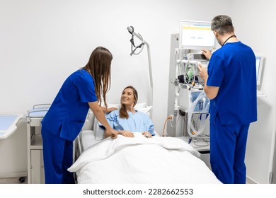 Hospital Ward: Friendly Doctor and nurse taking care of Beautiful Caucasian Female Patient Resting in Bed. Physician explains Test Results. Woman Recovering after Successful Surgery