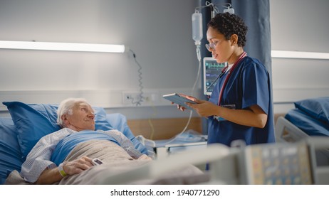 Hospital Ward: Friendly Female Head Nurse Making Rounds does Checkup on Elderly Patient Resting in Bed. She Checks Computer for Vitals while Old Man Fully Recovering after Successful Surgery - Powered by Shutterstock